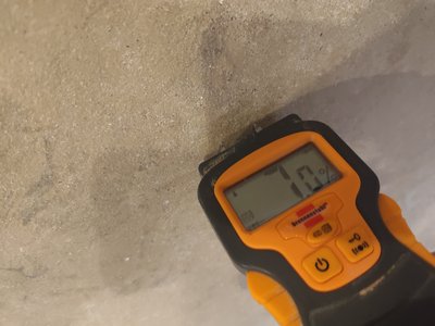 Moisture meter showing elevated levels at the floor