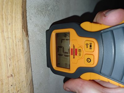 Moisture measurement — meter held against the basement
